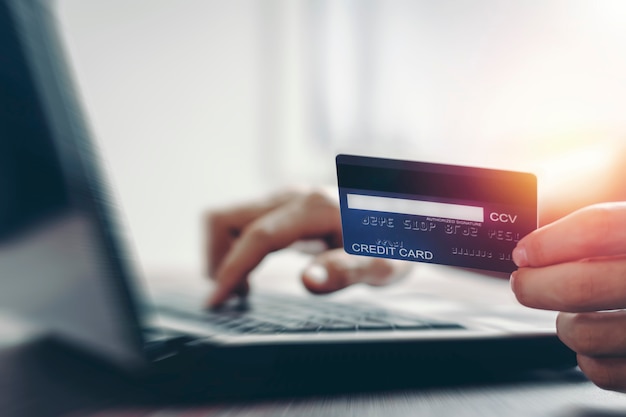 Tarjeta de crédito que realiza pagos en línea y compras por Internet por computadora portátil.