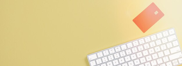 Tarjeta de crédito y teclado sobre un fondo amarillo Concepto de compras en línea Vista superior