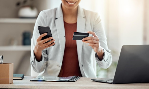 Foto tarjeta de crédito y teléfono para comprar y pagar productos en línea en una aplicación mientras está sentado en el trabajo banca profesional alegre, emocionada y alegre haciendo pagos y organizando las finanzas