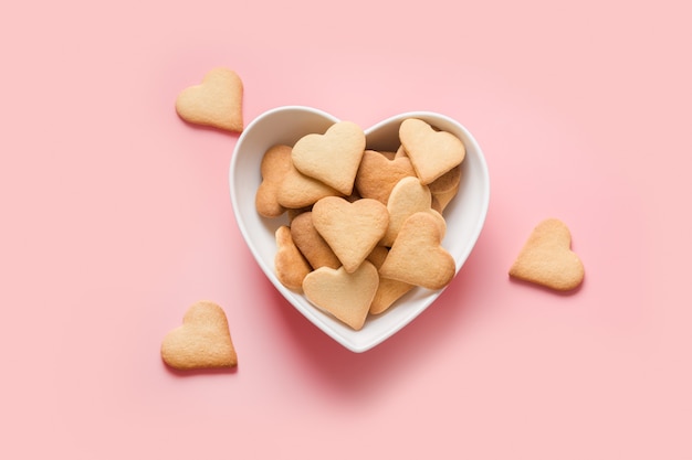 Tarjeta del día de San Valentín con galletas caseras en forma de corazón en la vista superior rosa