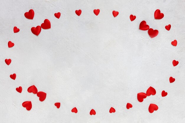 Tarjeta para el día de San Valentín con un marco de corazones textiles rojos sobre fondo blanco.