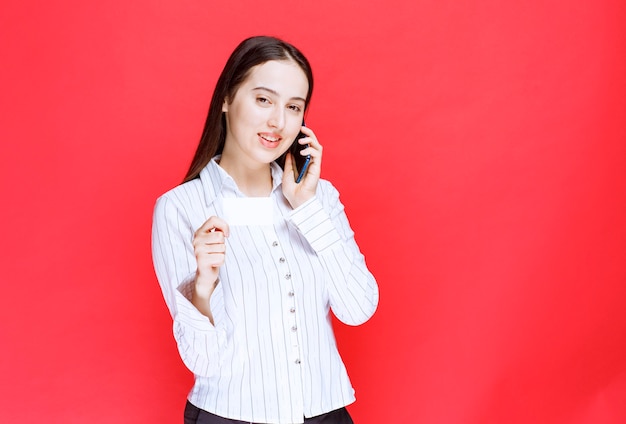 Tarjeta de empleado de oficina joven en su mano hablando con el cliente.