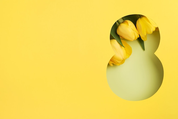 Tarjeta de felicitación del 8 de marzo Corte de papel Ocho hecha de fondo amarillo y flores frescas de primavera Ramo de tulipanes amarillos Tarjeta de felicitación para el Día de la Mujer el 8 de marzo Vista superior plana Día Internacional de la Mujer