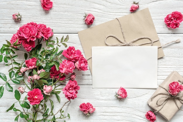 Tarjeta de felicitación blanca en blanco y caja de regalo con ramo de flores rosas rosadas