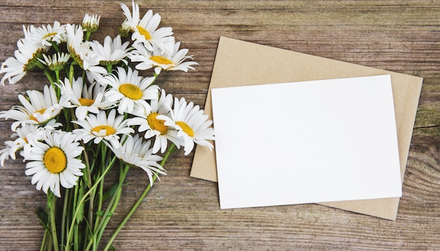 Tarjeta de felicitación blanca en blanco y sobre con flores de manzanilla