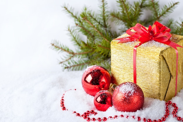 Tarjeta de felicitación blanca con espacio de copia para Navidad con regalo dorado y bola roja sobre nieve