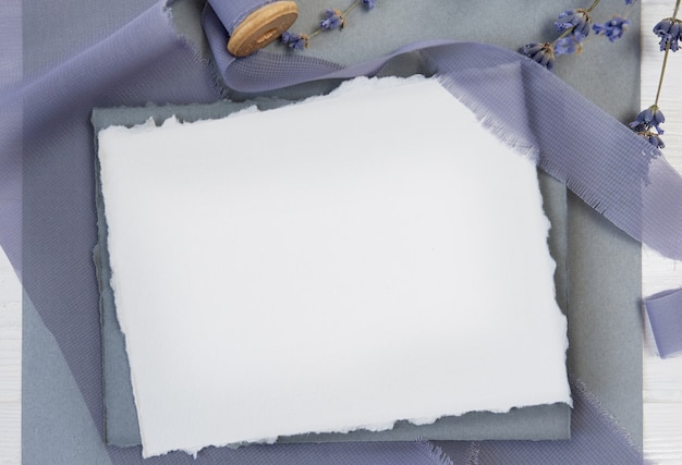Tarjeta de felicitación en blanco blanca sobre un fondo de tela azul con flores de lavanda