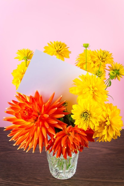 Tarjeta de felicitación en blanco en ramo de flores de verano amarillas sobre fondo rosa Invitación de vacaciones