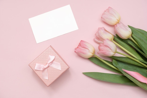 Tarjeta de felicitación en blanco con ramo de tulipanes rosas y caja de regalo