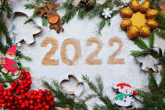 Foto tarjeta de felicitación creativa feliz año nuevo 2022 figuras de harina sobre un fondo de madera y ramas verdes