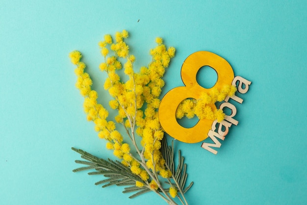 Tarjeta de felicitación para el Día Internacional de la Mujer 8 de marzo Fondo azul con un ramo de flores de mimosa y el número ocho de madera