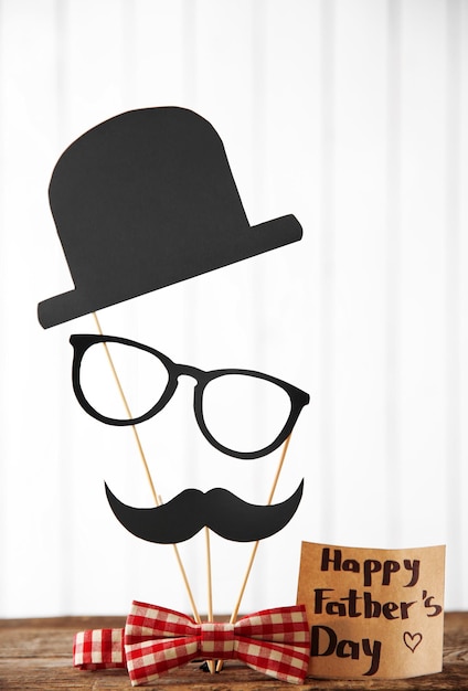 Foto tarjeta de felicitación para el día del padre feliz con sombrero de bigote de papel de pajarita y gafas en la mesa de madera