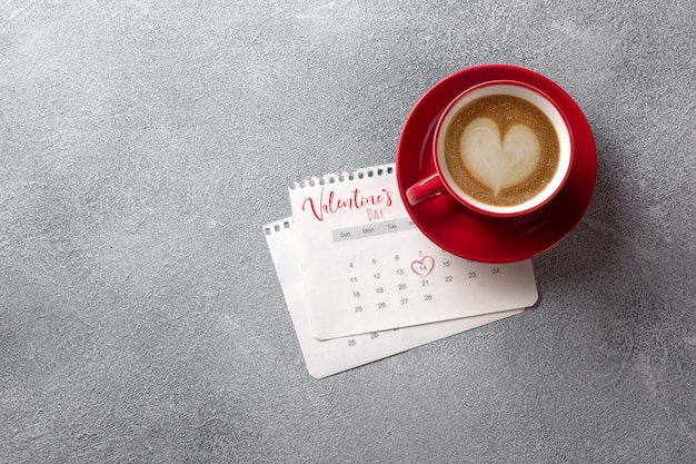 Tarjeta de felicitación del día de San Valentín. Taza de café rojo en el calendario de febrero. Vista superior