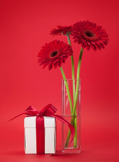 Tarjeta de felicitación con flores de gerbera y regalo.