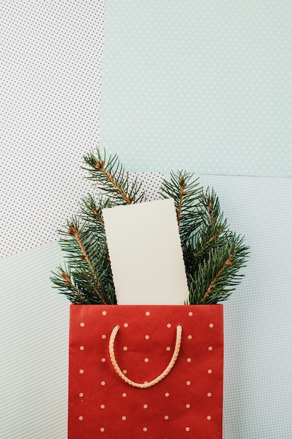 Tarjeta de felicitación de Navidad con papel vacío en blanco en bolsa con ramas