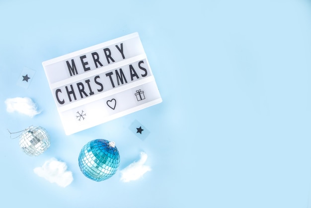 Tarjeta de felicitación de Navidad simple, invitación a fiesta, venta flatlay abstracto con bolas de Navidad de discoteca y tablero de luz, en la vista superior del espacio de copia de fondo azul claro