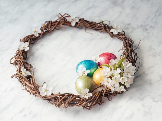 Tarjeta de felicitación de Pascua feliz con corona de Pascua, huevos teñidos y flores de primavera