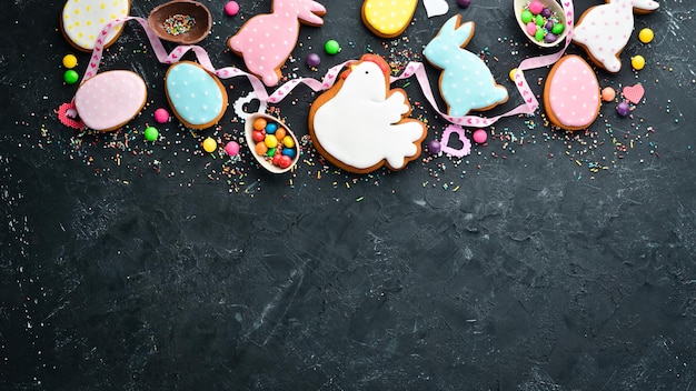 Tarjeta de felicitación de Pascua Feliz Pascua Galletas de jengibre de Pascua y huevos de colores decorativos Sobre un fondo negro Vista superior Espacio de copia libre