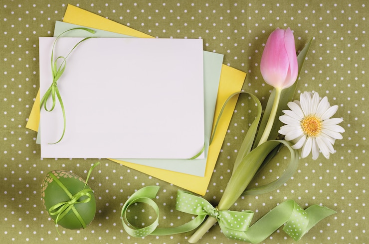 Foto tarjeta de felicitación de pascua con flores, huevo y cintas.