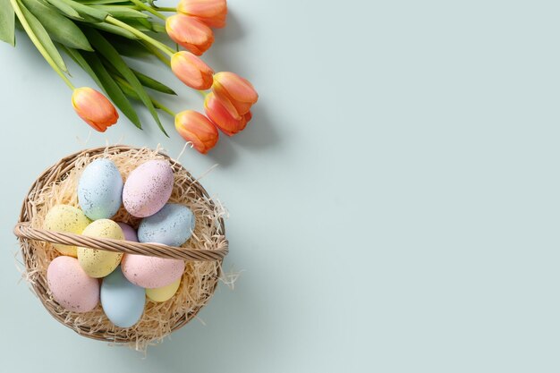 Tarjeta de felicitación de Pascua con huevos en canasta y tulipanes en azul Vista desde arriba Copiar espacio