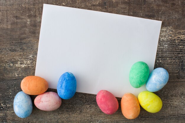 Tarjeta de felicitación de Pascua y huevos de Pascua en mesa de madera