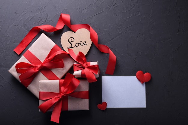 Tarjeta de felicitación de San Valentín fondo símbolos de amor, decoración roja con cajas de regalos en la mesa de piedra. Vista superior con espacio de copia y texto.