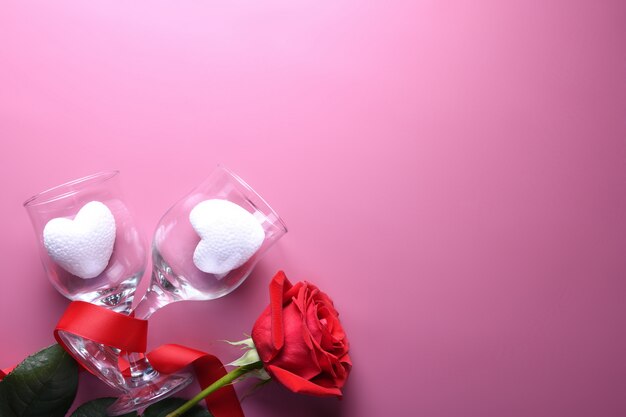 Tarjeta de felicitación de San Valentín fondo símbolos de amor, decoración roja con gafas sobre fondo rosa. Vista superior con espacio de copia y texto.