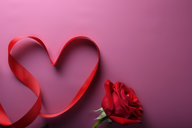 Tarjeta de felicitación de San Valentín fondo símbolos de amor, decoración roja con rosas sobre fondo rosa. Vista superior con espacio de copia y texto.