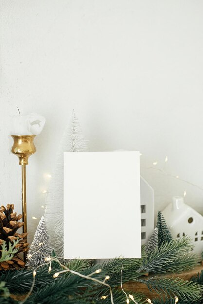 Tarjeta de felicitación vacía sobre el fondo de casas de Navidad elegantes ramas de abeto con luces doradas y decoraciones de árboles tarjeta de Navidad maquillaje de espacio para texto plantilla de felicitaciones de temporada