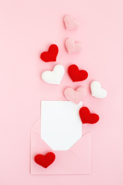 Tarjeta de feliz día de San Valentín con corazones de color rosa, blanco y rojo sobre fondo rosa. Mensaje de amor.