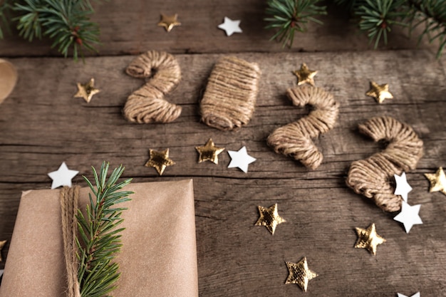 Tarjeta festiva con fecha 2022 sobre fondo de madera y decoraciones de Navidad y Año Nuevo
