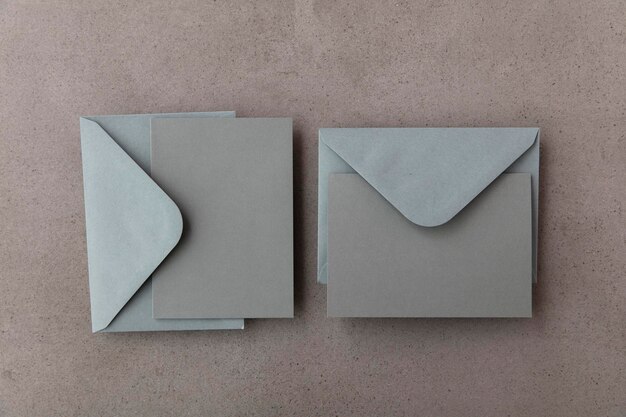 Tarjeta gris en blanco con plantilla de sobre de papel gris maqueta sobre un fondo concreto