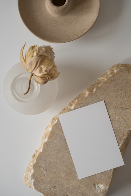 Tarjeta de hoja de papel en blanco con espacio de copia de maqueta, flor seca, piedra de mármol