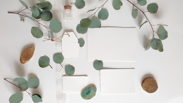 Foto tarjeta de invitación de felicitación de boda blanca en blanco, etiqueta, ágata, rama de hojas de eucalipto plateado, sobre fondo de mesa de papel con textura. plantilla moderna elegante vista superior plana