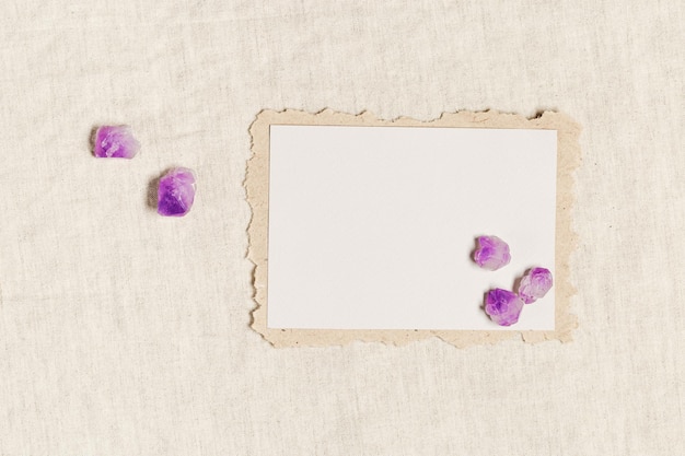 Tarjeta de invitación vacía tarjeta en blanco con piedra curativa de cristal natural amatista púrpura sobre mantel
