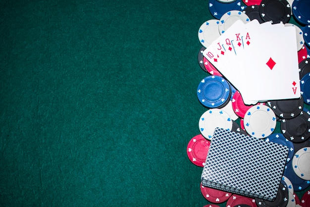 Tarjeta de juego Royal Flush sobre las fichas de casino en la mesa de póquer verde