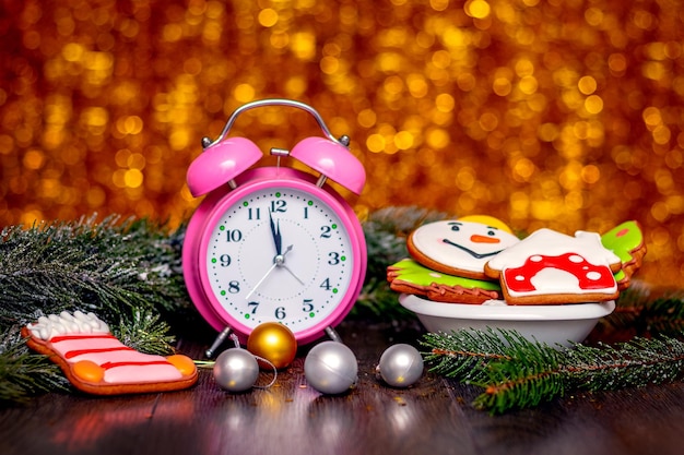 Tarjeta de Navidad y Año Nuevo con un reloj Rama de abeto de galletas de Navidad y adornos navideños en un fondo de bokeh brillante