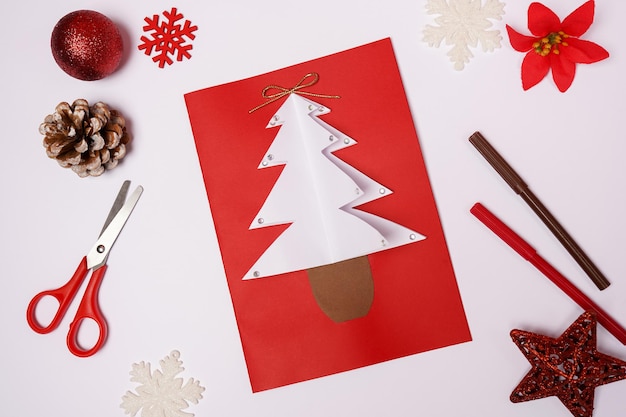 Foto tarjeta de navidad de bricolaje con abeto de papel de colores sobre fondo blanco.