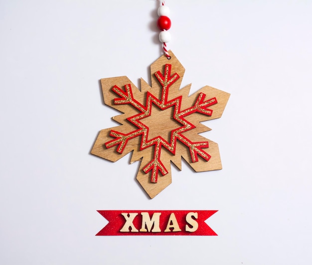Tarjeta de Navidad copo de nieve de madera con letras de Navidad sobre fondo blanco.