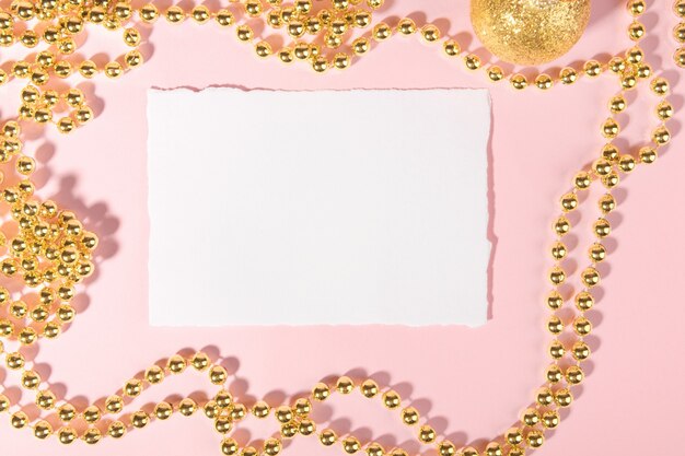 Tarjeta de Navidad con decoración festiva dorada sobre un fondo rosa pastel.