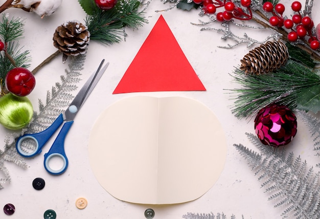 Tarjeta de Navidad DIY paso a paso. De papel de colores y algodón Doble la hoja por la mitad y corte el círculo hasta el suelo. De otra hoja de papel un triángulo.