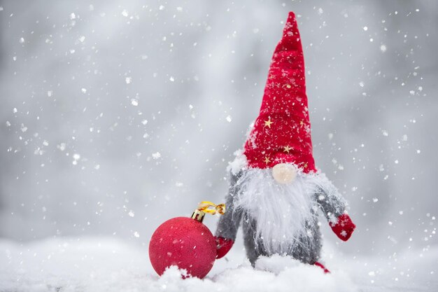 Una tarjeta de Navidad Un enano lindo con un sombrero rojo sobre un fondo de invierno