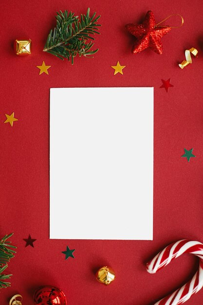 Foto tarjeta de navidad endecha plana moderna tarjeta de felicitación simulada con elegantes adornos navideños sobre fondo rojo plantilla de postal vacía con espacio para texto feliz navidad y felices fiestas