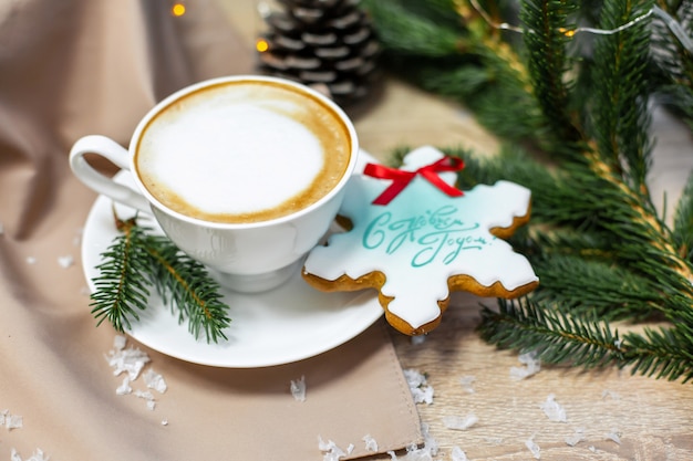 Tarjeta de Navidad y feliz año nuevo con taza de café, pino, rama de abeto y pan de jengibre en mesa de madera