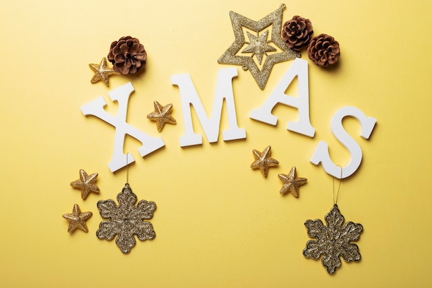 Tarjeta de Navidad con letras y decoración navideña en la superficie amarilla. Concepto de Navidad, vista de arriba hacia abajo