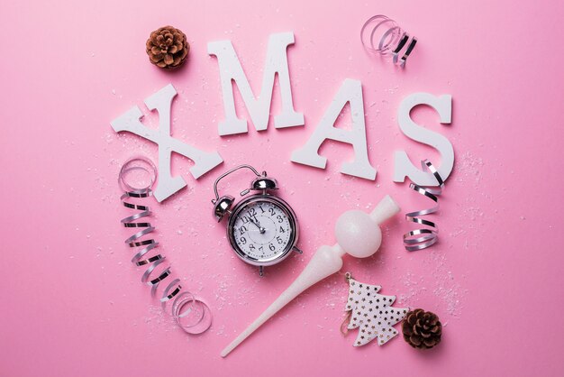 Tarjeta de Navidad con letras y reloj sobre fondo rosa. Concepto de Navidad, vista de arriba hacia abajo