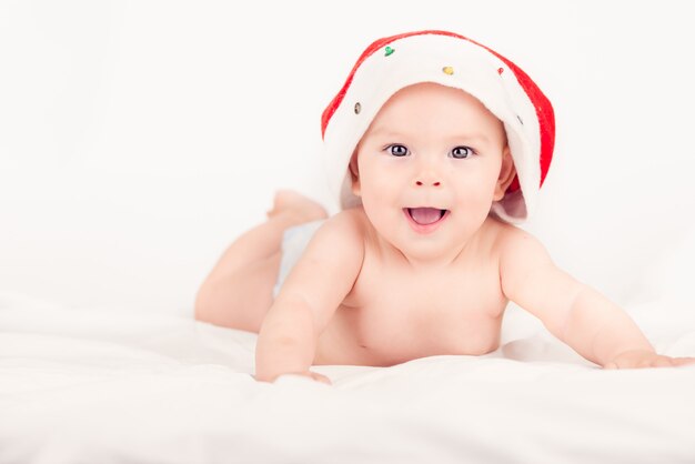 Tarjeta de Navidad con una linda niña con un sombrero rojo de santa en un fondo de briht aireado beige con copia