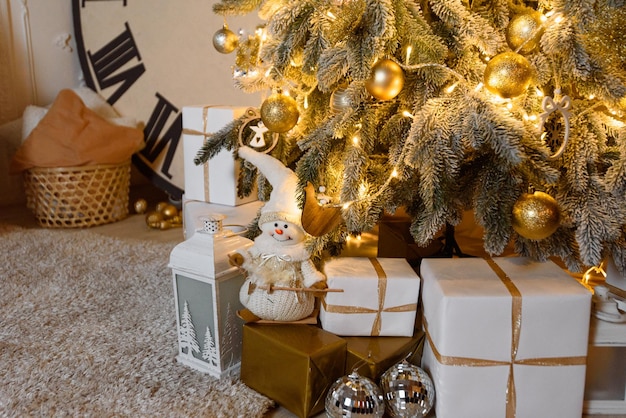 Tarjeta de Navidad con muñeco de nieve debajo del árbol Regalos Abeto cubierto de nieve y reloj grande