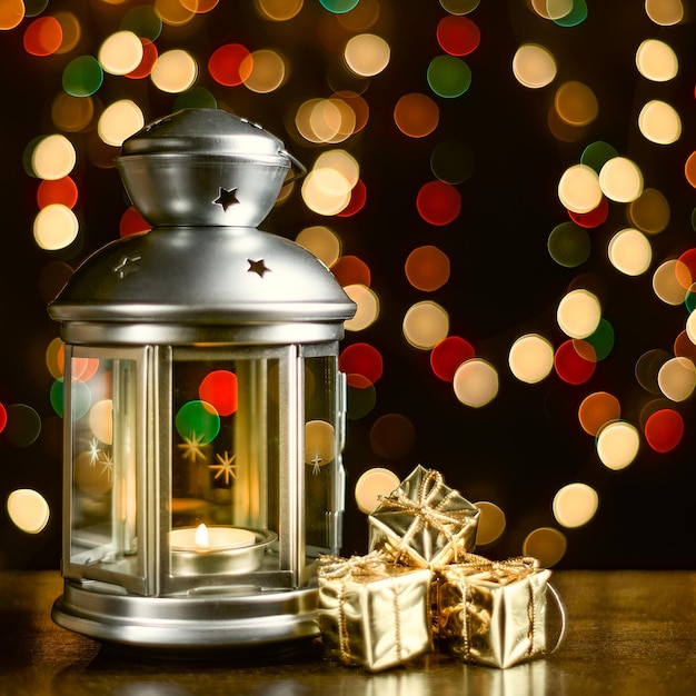 Tarjeta de Navidad un muñeco de nieve una linterna con velas cajas brillantes brillantes con regalos y luces borrosas