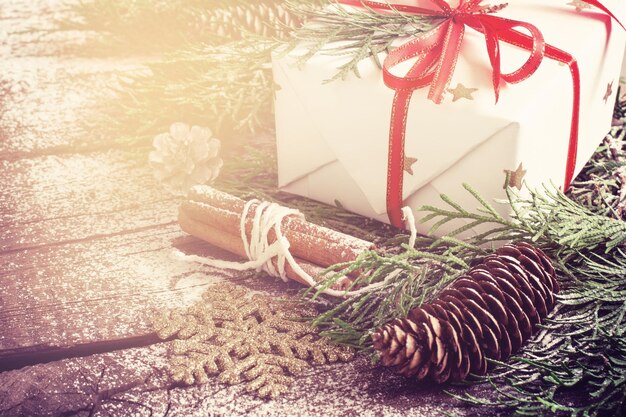 Tarjeta de navidad con regalo y ramas de coníferas y conos de cerca